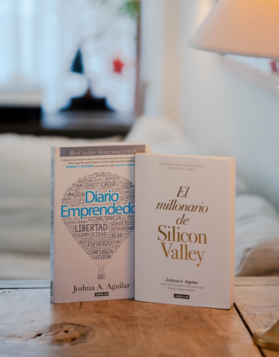 Two of Joshua's books standing on a wooden table: Diario Emprendedor and El millonario de Silicon Valley.