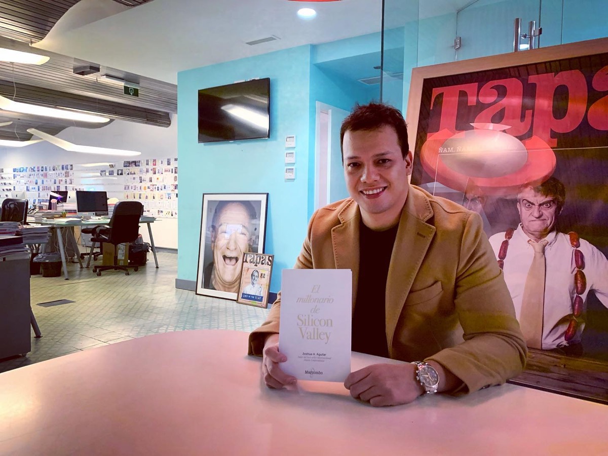 Joshua sonriendo en una mesa de la redacción de Forbes, con El millonario de Silicon Valley